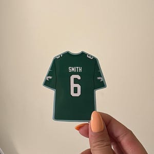 May include: A dark green sports jersey sticker featuring the name SMITH and the number 6 in white lettering on the back, with smaller white numbers 6 on each shoulder sleeve, designed with a clean white border around the entire jersey shape.
