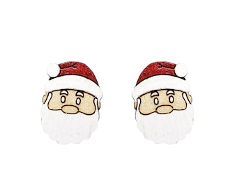 Puede incluir: Un par de pendientes de madera con forma de Papá Noel. Cada pendiente tiene un gorro rojo, una barba blanca y una cara marrón con una expresión de dibujos animados.