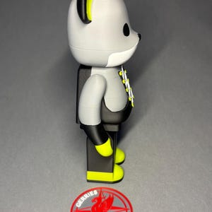 May include: A gray and black bear-shaped figurine with yellow accents on the ears and feet. The figurine has a white chest and a black torso. A red and gray logo with the word "GERRIES" is at the base.