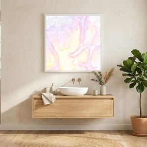 May include: A modern bathroom interior featuring a floating wooden vanity with a white vessel sink, gold fixtures, and a framed abstract art piece. A large oval mirror and a potted plant add to the minimalist design. The color palette is neutral with soft pink and yellow tones.