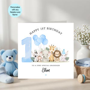 May include: A square greeting card featuring a large blue number one, blue balloons, and watercolour illustrations of a zebra, monkey, elephant, giraffe, lion, and hippo. Text reads Happy 1st Birthday to a very special grandson and the name Ethan.
