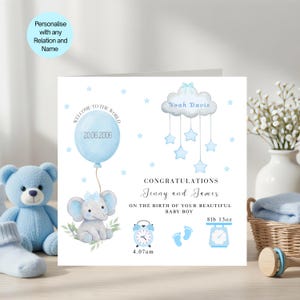 May include: A square greeting card featuring a blue elephant holding a balloon with the date 20.06.2006, a cloud mobile with the name Noah Davis, an alarm clock showing 4.07am, baby footprints, and a scale reading 8lb 13oz for a baby boy.