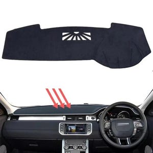 May include: A black dashboard cover featuring a sunburst cut-out design. The cover is designed to fit a car dashboard, as seen in the image. The cover is placed on the dashboard of a car, with the steering wheel and other interior components visible.