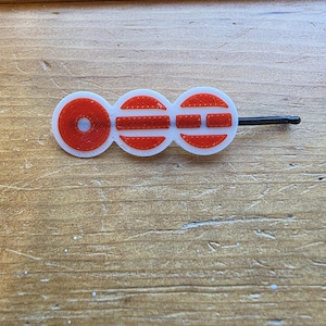 Può includere: Fermaglio per capelli decorativo bianco e rosso con spilla nera. La clip presenta tre forme collegate: un cerchio rosso e due ovali bianchi con dettagli rossi. La forcina misura circa 6 cm di lunghezza.