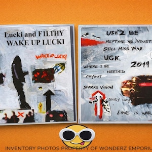 May include: CD case with abstract artwork. The left side reads "Lucki and Filthy Wake Up Lucki" with additional text and graphics. The right side features text including "Use 2 Be" and "2019", plus a car illustration. The background is a mix of colors.