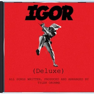 Puede incluir: Una caja de CD roja con la palabra "IGOR" en letras negras grandes. Una imagen en blanco y negro de una persona en movimiento está en el centro. El texto "(Deluxe)" y texto adicional están presentes.