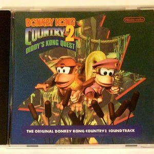 May include: A CD case for Donkey Kong Country 2: Diddy's Kong Quest. The cover shows the game's title and two cartoon monkeys. The background is a jungle scene with the Nintendo logo.