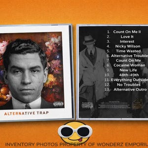 May include: A CD case with a black and white image of a man on the front cover, with the words "ALTERNATIVE TRAP" in orange. The back cover lists song titles. The image has a parental advisory warning.