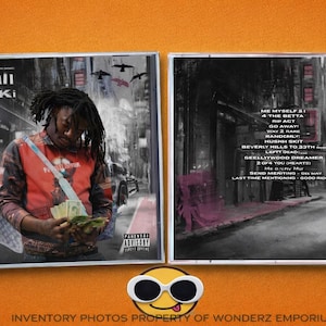 May include: A CD case featuring the album art for Lucki's album. The cover art shows a person holding money in front of a city backdrop. The CD case also displays the album's tracklist and a parental advisory warning.