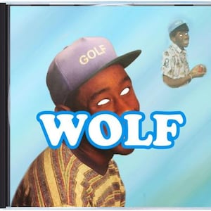 Puede incluir: Caja de CD con arte de álbum. La imagen muestra a una persona con una gorra morada con "GOLF" y la palabra "WOLF" en azul y blanco. Una segunda imagen de la persona está en el fondo. El fondo es azul claro.