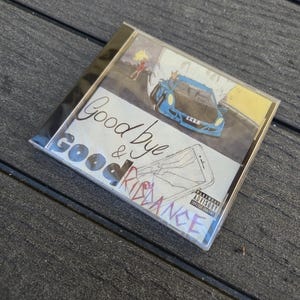 Puede incluir: Una caja de CD con el título "Goodbye & Good Riddance" en una fuente manuscrita. La portada presenta un coche azul y una persona. La caja tiene una advertencia para padres.