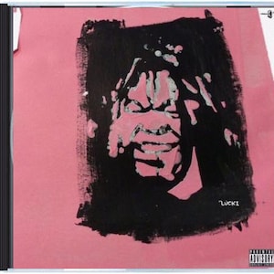 May include: A CD case with a pink background and a black and pink abstract painting. The painting appears to be a face or figure. The word "Lucki" is written in white. An advisory warning is in the bottom right corner.
