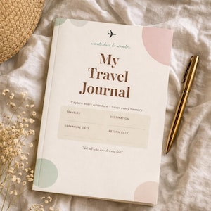 May include: A white travel journal with the text "My Travel Journal" and the phrase "wanderlust & wonder." The journal includes sections for traveler, destination, departure and return dates. A gold pen rests beside the journal.