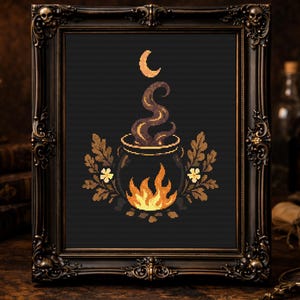 Może przedstawiać: Oprawiony haft krzyżykowy przedstawiający czarny kocioł z płomieniami, parą i półksiężycem. Kocioł otoczony jest liśćmi i kwiatami. Rama jest ozdobna i ciemna, z napisem "Mysterious Raven" na dole.