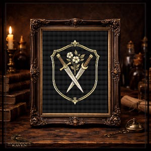 May include: An ornate, dark brown framed cross-stitch design. The design features a shield with crossed swords and floral accents in gold and white on a black background. The frame sits on a wooden surface, with a candle and books in the background.