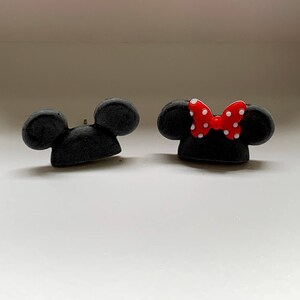May include: A pair of black Mickey Mouse ears with a red bow with white polka dots on one ear.