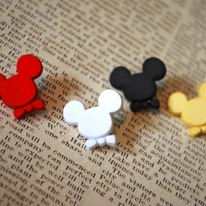May include: Four wooden Mickey Mouse head ornaments in red, black, white, and yellow. Each ornament has a bow tie.