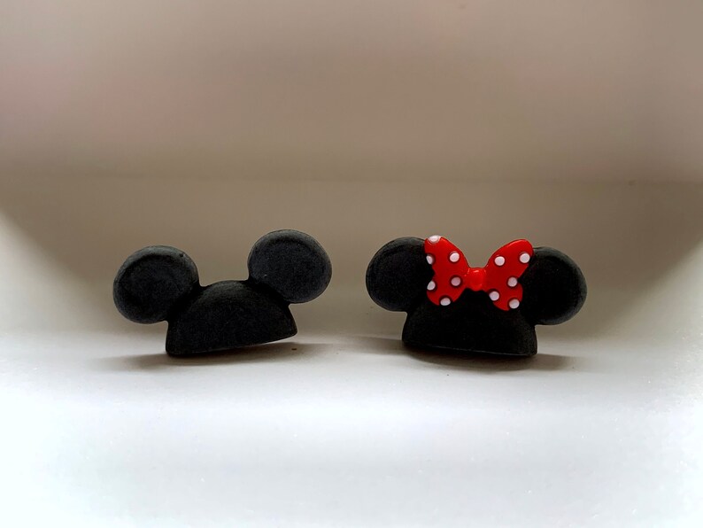 May include: Two black mouse ears, one with a red bow with white polka dots.