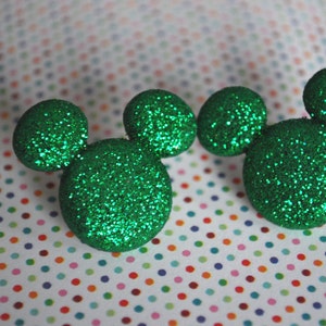 May include: Two green glitter Mickey Mouse ears. The ears are made of a soft, sparkly material and are perfect for adding a touch of Disney magic to any outfit.