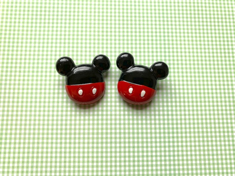 Op de afbeelding: Twee zwarte en rode Mickey Mouse-knoppen met witte ogen.