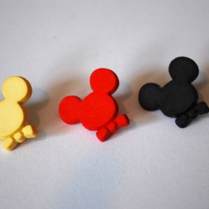 May include: Three wooden Mickey Mouse head ornaments in yellow, red, and black.