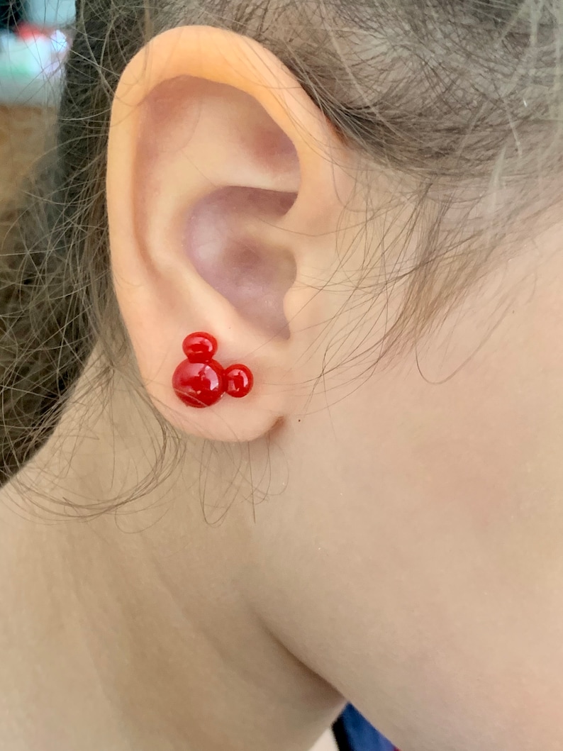May include: Red Mickey Mouse stud earrings. The earrings are small and feature a classic Mickey Mouse silhouette.