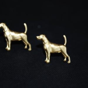 May include: A pair of gold-colored dog-shaped cufflinks. The cufflinks are detailed and realistic.