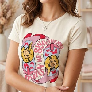 Pode incluir: Camiseta creme com um gráfico de botas de cowboy rosa e azul, o rosto de uma mulher loira e as palavras "Sweetheart Orion". O texto "Boutique Craftsmanship | Print-Ready Design" está na parte inferior.