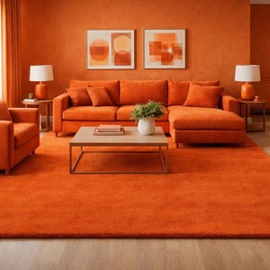 Puede incluir: Un salón moderno con una combinación de colores naranja. La habitación cuenta con un sofá seccional naranja, un sillón, una alfombra y pintura mural. Dos obras de arte abstractas enmarcadas cuelgan de la pared. Dos lámparas con pantallas blancas están sobre las mesas auxiliares.