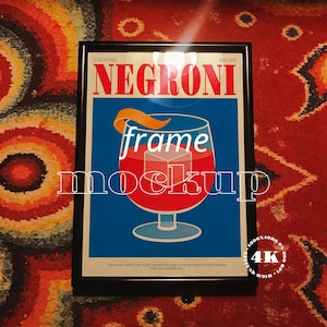 Può includere: Stampa incorniciata con la ricetta del cocktail Negroni. L'immagine mostra un bicchiere da cocktail con un liquido rosso, cubetti di ghiaccio e una scorza d'arancia. La parola "Negroni" è in rosso su sfondo blu.