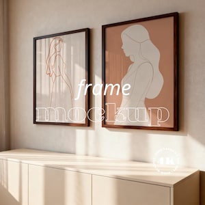 May include: Two framed art prints with minimalist line drawings of women. The frames are dark brown, and the artwork features a peach and white color scheme. The text "frame mockup" is overlaid on the image. The artwork is displayed above a light-colored cabinet.