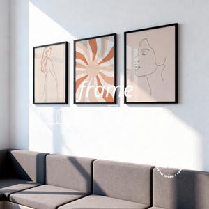 Può includere: Tre stampe artistiche incorniciate. Le stampe presentano disegni a linea minimalisti di una donna, un motivo a raggiera e un profilo di donna. Le cornici sono nere e le opere d'arte sono nelle tonalità del beige, dell'arancione e del marrone. La parola "frame" è stampata sull'immagine.
