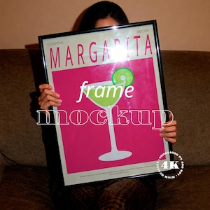 May include: A framed poster with a margarita recipe design. The poster features a pink background with a lime green margarita glass illustration and the word "Margarita" in large letters. The frame is black.