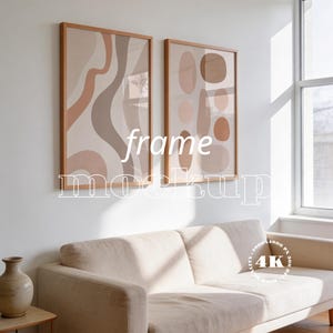 May include: Two framed abstract art prints with neutral colors hang above a beige sofa. The artwork features organic shapes in shades of brown, beige, and gray. The text "frame mockup" is overlaid on the image.