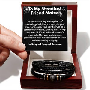 May include: A black braided leather bracelet with a magnetic clasp engraved with the words love you forever, featuring metallic beads, presented in a dark wood box with a card reading To My Steadfast Friend Mateo and a message of respect.