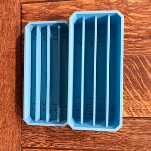 May include: Two light blue rectangular organizers with vertical dividers. The smaller organizer has measurements of 1/2", 5/8", 3/4", and 1". The larger organizer has measurements of 1 1/4", 1 1/2", 1 3/4", and 2".