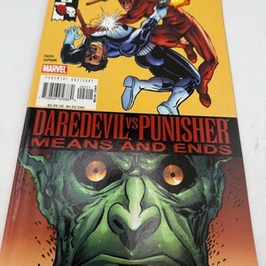 May include: A comic book titled "Daredevil vs Punisher: Means and Ends." The cover features illustrations of Daredevil and Punisher in action against a yellow background. The bottom half displays a green monster face. The Marvel Comics logo is visible.