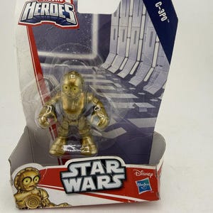 May include: A gold-colored C-3PO action figure from the Star Wars Galactic Heroes collection. The figure is in a clear plastic package with a Star Wars logo and the Disney and Hasbro logos. The packaging also includes the text "C-3PO".