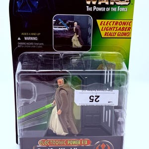 May include: A Star Wars The Power of the Force action figure of Ben (Obi-Wan) Kenobi in original blister packaging. The figure wears a brown robe and holds a green electronic lightsaber. The packaging features the Star Wars logo and text.