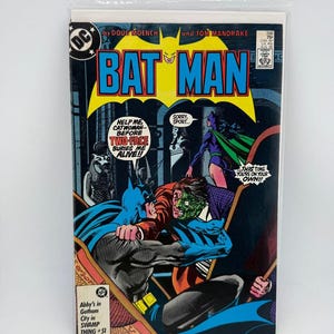 May include: A Batman comic book issue 398, dated August 1986, featuring a cover illustration of Batman grappling with Two-Face while Catwoman stands nearby. The text reads Help me Catwoman before Two-Face buries me alive, Sorry sport, and This time you're on your own.