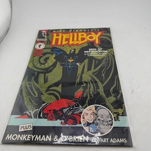 May include: A Hellboy comic book titled "Seed of Destruction" by Mike Mignola, with "Monkeyman & O'Brien" and "Art Adams" printed on the cover. The cover features a red character with horns, green tentacles, and the word "Hellboy" in yellow.