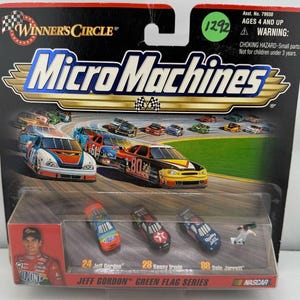 May include: A Micro Machines NASCAR set featuring miniature race cars. The packaging includes the text "Winner's Circle" and "Micro Machines." The set includes three small cars and a miniature figure. The cars are labeled with the numbers 24, 28, and 88.
