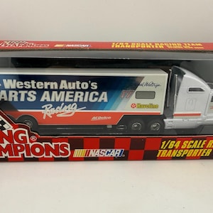 May include: A 1/64 scale Racing Champions die-cast transporter truck. The trailer is white with blue and red graphics for Western Auto's Parts America Racing. The cab is white with red accents. The box reads "1/64 Scale Racing Team Transporter".