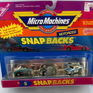 May include: A Micro Machines Snap Backs motorized toy car set in original packaging. The card features red, blue, and yellow graphics with the text Micro Machines and Snap Backs. Inside the clear plastic blister are three miniature toy cars.