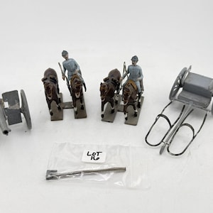 May include: A collection of antique toy soldiers and military vehicles. Includes a gray cannon, a horse-drawn carriage with two soldiers, and a small cart. The figures are painted in muted colors.