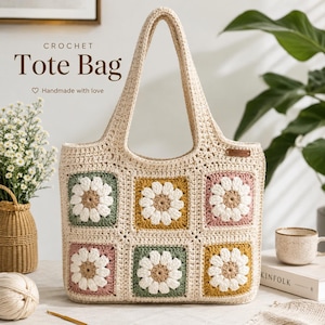 May include: A cream-colored crochet tote bag featuring a grid of six square motifs, each displaying a white daisy with a tan center. The squares are bordered by sage green, mustard yellow, and dusty rose yarn. Text reads: CROCHET Tote Bag.