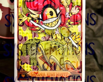 May include: A rectangular trading card featuring a cartoon character with bright pink hair and a wide, toothy grin. The character wears a yellow dress with kiwi-patterned details. The background includes pink cherry blossoms and kiwi slices. The text reads SAKURA KIWI NIFFTY.