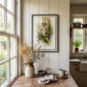 Watercolor owl printable wall art displayed in black frame on white shiplap farmhouse kitchen wall above rustic wood table with dried wheat stems and stoneware pottery, instant digital download