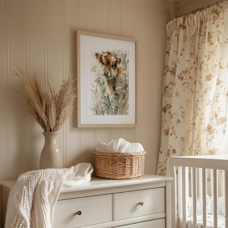 Watercolor highland cow calf printable wall art in natural wood frame displayed above white nursery dresser, cottagecore farmhouse baby room with floral curtains, pampas grass, and wicker basket, instant digital download