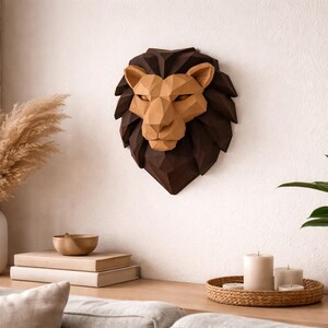 May include: A geometric lion head wall decor in shades of brown and tan hangs on a white wall. The lion's mane is dark brown, and the face is a lighter tan color. The decor is a striking piece of art.